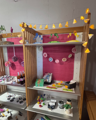 Verkaufsregal mit Produkten, wie Lichterkette, Sirup, Geschenkpapier, Upcycling-Taschen und Mitbringselgeschenken Alle gefertigt von MItarbeitern der Stiftung MBF.