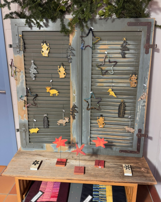 Dekorative alte Fensterläden, die an der Wand gelehnt stehen und mit weihnachtlichen Hängern dekoriert sind.