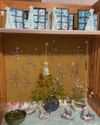 Holzregal in unserm Lädeli mit Töpferarbeiten und dekorativen Stern-Aufhängern aus Draht