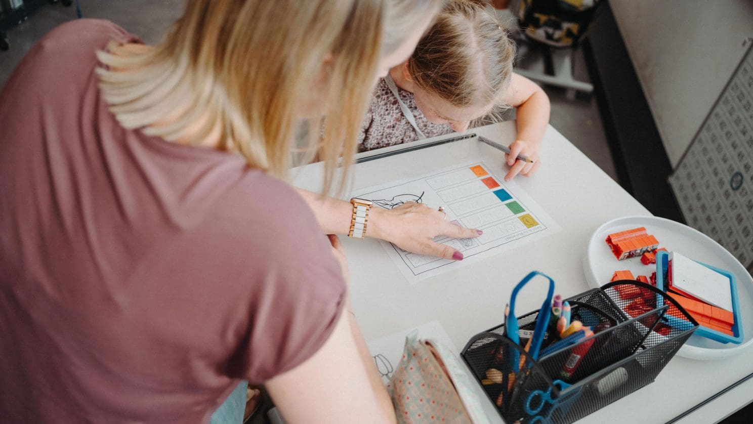 Lehrperson unterstützt Mädchen beim Schreiben lernen – individuelle Förderung an der heilpädagogischen Schule.