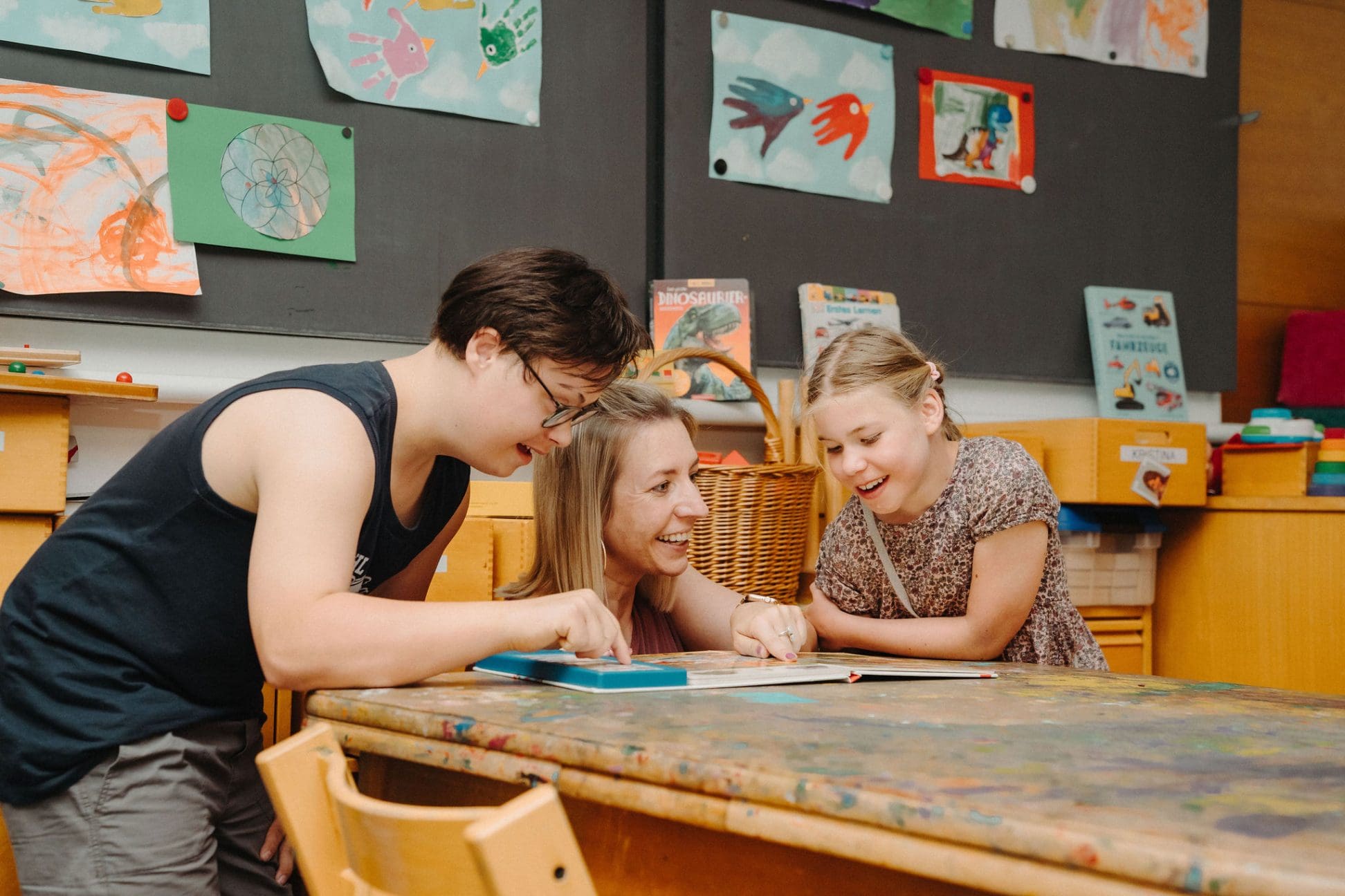 Lernmoment in der HPS: Kinder mit Betreuerin entdecken gemeinsam ein Buch im Unterricht.