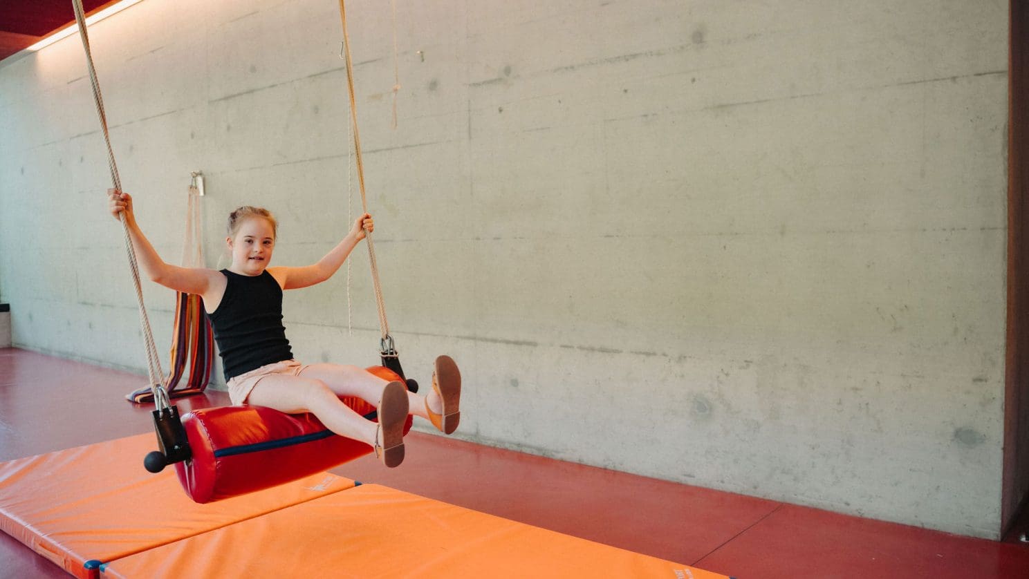 Bewegung und Spaß: Schülerin schwingt an der Therapieschaukel in der HPS Turnhalle.
