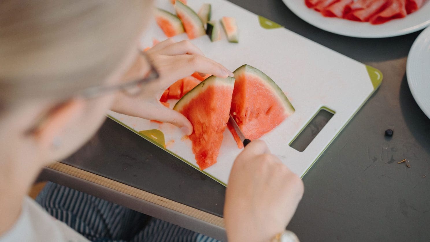Mit allen Sinnen lernen – Kind schneidet Obst und erlebt Selbstständigkeit im Alltagstraining.