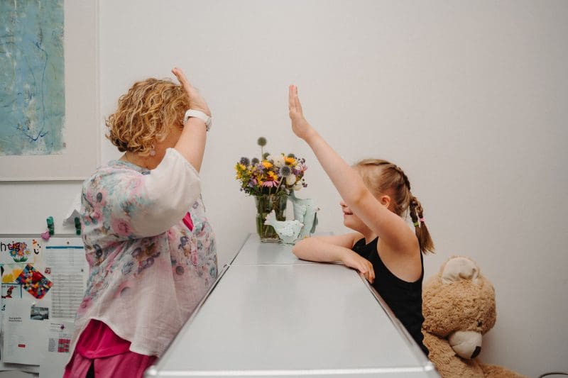 Fröhliches High Five zwischen Betreuerin und Kind – gelebte Inklusion.