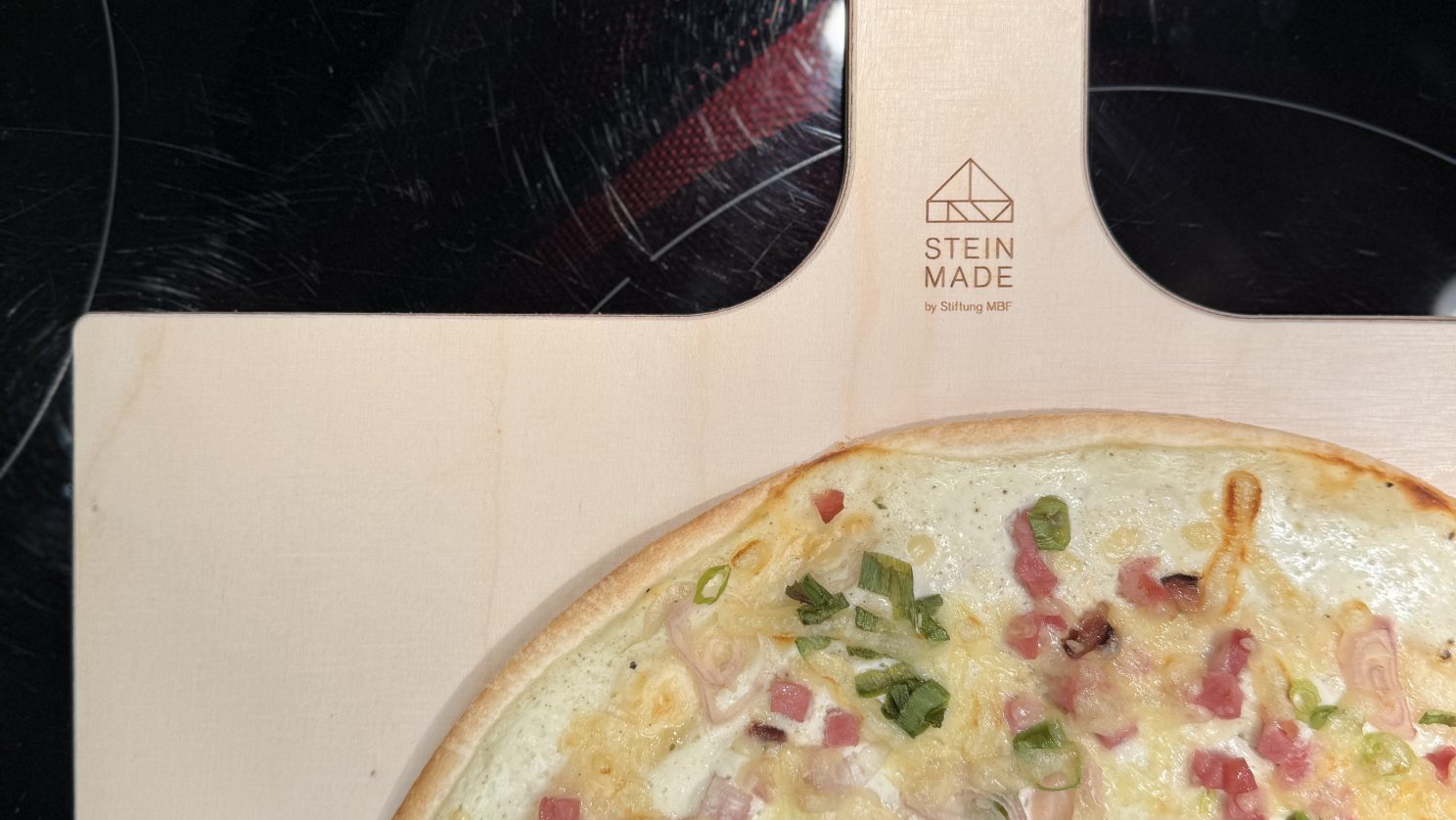 Stein Made Flammkuchenbrett mit einem Flammkuchen darauf.