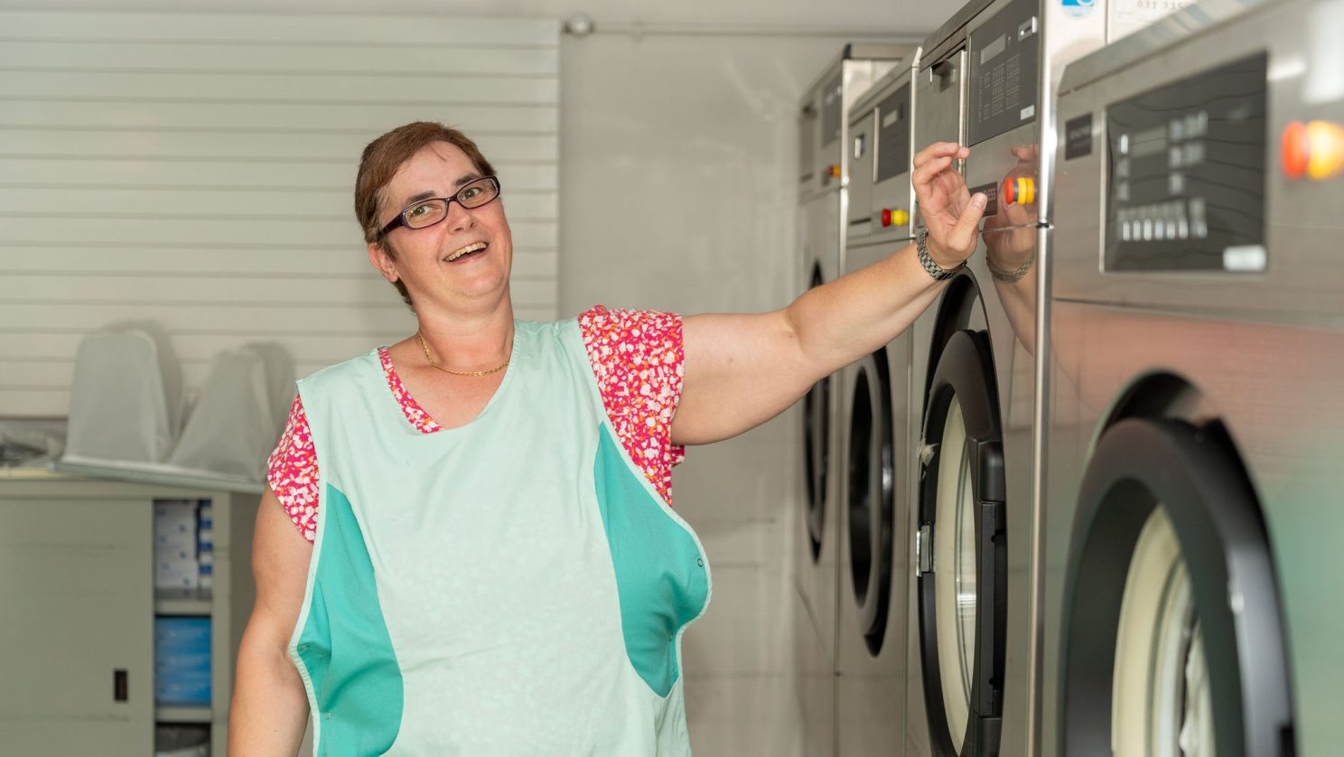 Mitarbeiterin arbeitet lachend in der Wäscherei der Stiftung MBF – Freude am Arbeitsplatz.