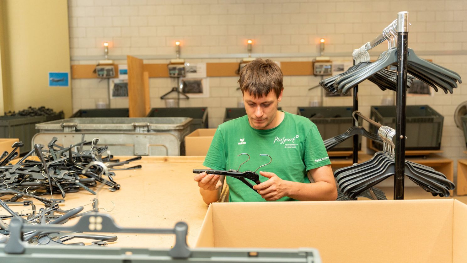 Inklusive Arbeitsumgebung bei der Stiftung MBF – Mitarbeitender sortiert und prüft Kleiderbügel.