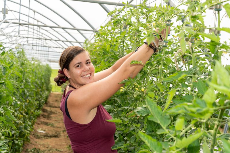 Lächelnde Gärtnerin im MBF-Gewächshaus pflegt Pflanzen - abwechslungsreicher Arbeitsplatz in der Garten- und Landwirtschaft.