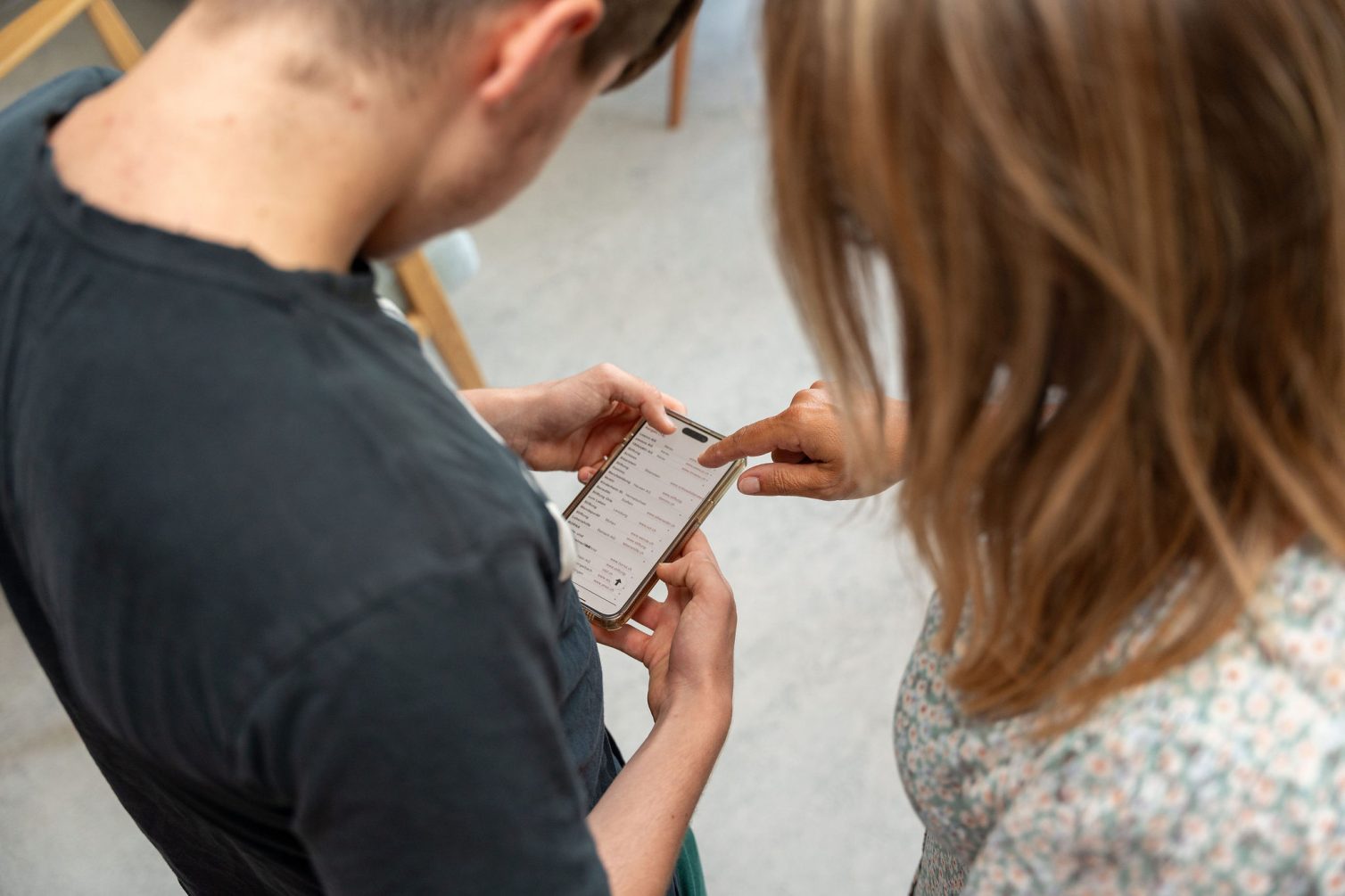 Begleitung im Alltag: Mitarbeitende erklärt einer Person mit Unterstützungsbedarf etwas auf dem Smartphone.