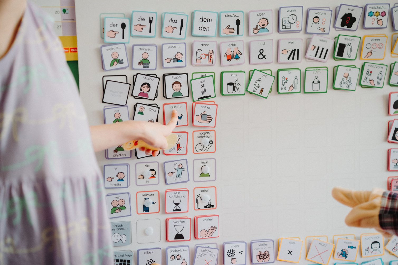 Gemeinsames Arbeiten an einer METACOM-Tafel: Zwei Hände zeigen auf verschiedene Symbolkarten.